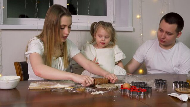 A family of three making homemade shaped cookies together