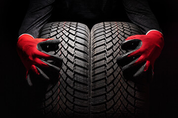 Car tire service and hands of mechanic holding new tyre on black background with copy space for text