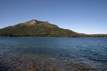 View of Gutierrez lake in Bariloche, Patagonia Argentina. The turquoise water, rocky shallows and mountains in the horizon.