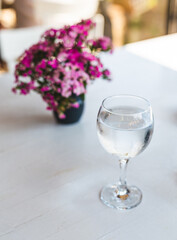 close up of a fancy glass of fresh water an flowers on white clean table in a restaurant