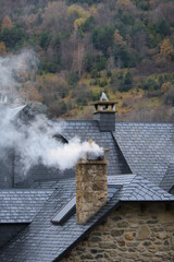 Peque&ntilde;a casa europea con una chimenea humeante. Humo desde una chimenea encendida quemando le&ntilde;a. Madera prendida en una chimenea