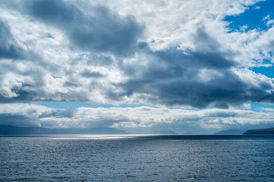 View from the Iceland ferry Norrona when approaching the Faroe Islands over blue ocean water and clouds in the sky; Faroe Islands, Denmark