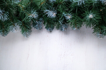 light wooden background and green coniferous branch on top.christmas garland without decorations.