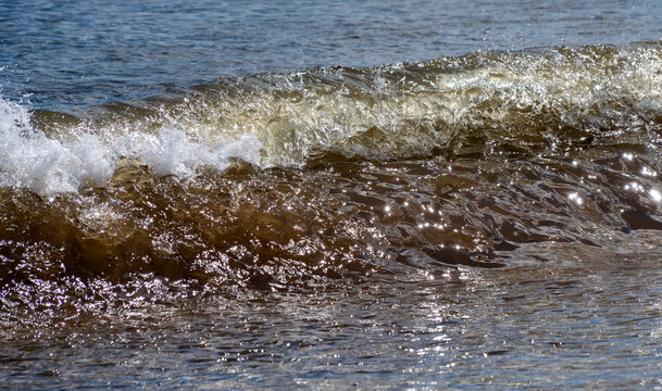 Sunlight illuminates the surf rolling into shore; South Shields, Tyne and Wear, England