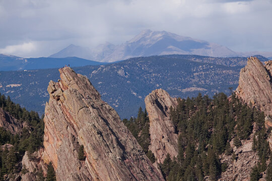 Climbers summit the famous flatirons with Longs peak in the Distance.