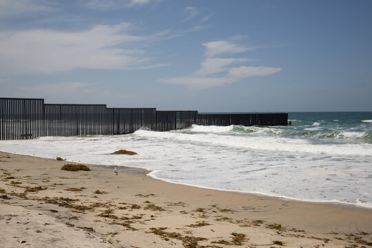 A fence marks the United States/Mexico border where it meets the Pacific Ocean.