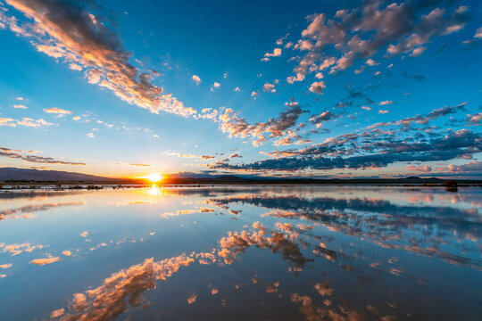 Sunfair dry lake bed is filled with water after a rare rainstorm, reflecting the sunset in the remaining clouds.
