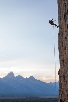 Climber rappelling down boulder.