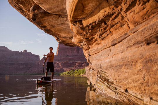 A man stand up paddleboarding on the Colorado River, Utah.