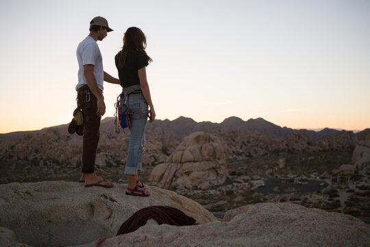 A young couple take in the sunset after climbing The Eye route on Cyclops Rock in Joshua Tree National Park.