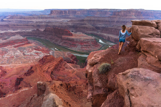 A Woman Steps Up To The Edge Of The Horseshoe Bend Viewpoint.