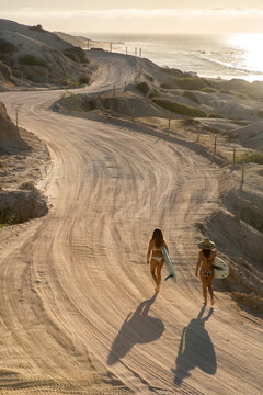Two women search for waves on the coast of Cabo at sunrise.