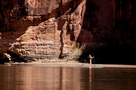 A young woman paddleboarding on the Colorado River in Utah.
