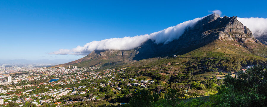 Cloud formation creating the tablecloth effect over Table Mountain with an overview of Cape Town city skyline from Signal Hill; Cape Town, Western Cape Province, South Africa