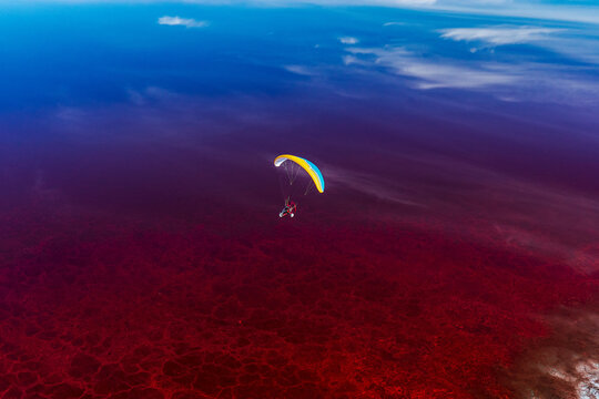 A paramotor pilot flies over Owens Lake, turned red from halobacteria, Lone Pine, California, USA