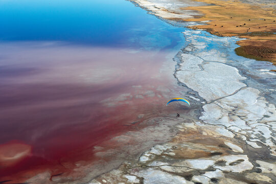 Paramotor flies over Owens Lake, turned red from halobacteria, Lone Pine, California, USA