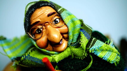 puppet for the epiphany of a old witch with glasses and kerchief on the head. white background, copy space