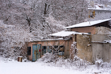Opuszczone zabudowania przemysłowe wśród drzew pod puszystą kołderką śniegu .
