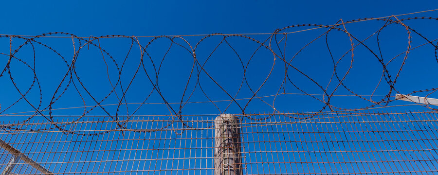 Barbed wire fence against a blue sky at Robben Island Prison; Robben Island, Cape Town, Western Cape Province, South Africa