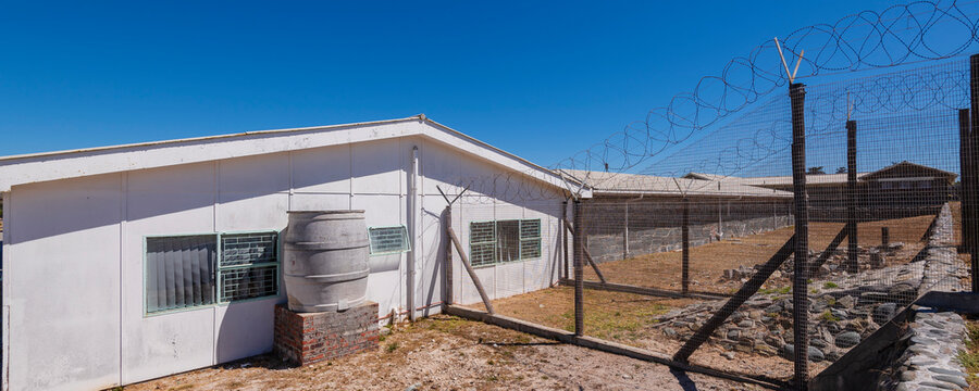 Barbed wire fence and buildings at Robben Island Prison; Robben Island, Cape Town, Western Cape Province, South Africa