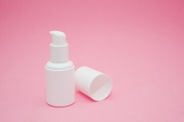 Serum bottle with water drops on a pink gradient background
