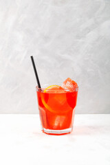 Refreshing iced drink. Glass of Red cold cocktail with ice cubes and drinking straw