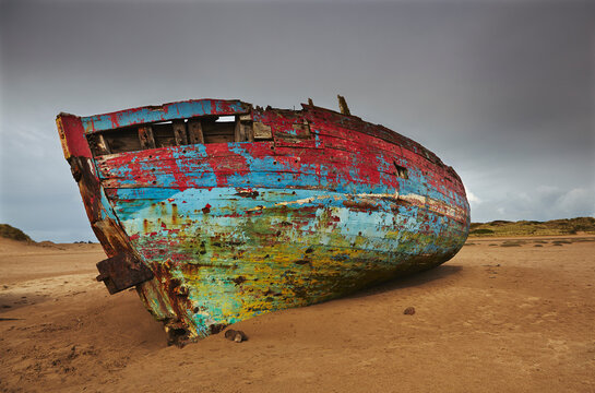 Colourful weathered shipwreck lying in sand dunes at Crow Point, at the mouth of the Taw and Torridge Rivers, near Barnstaple, Devon, Great Britain; Devon, England