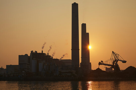 A silhouette of a coal-fired power station at sunset, Lamma Island, Hong Kong.; Yung Shue Wan, Lamma Island, Hong Kong, China.