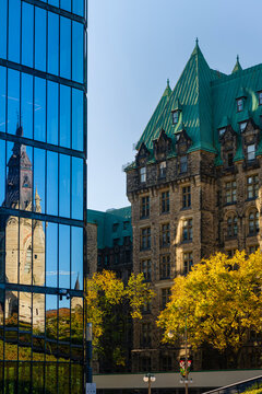 West Block of the Canadian Parliament Buildings and Canadian Parliament House reflected in the glass facade of a building in the nation's capital city of Ottawa; Ottawa, Ontario, Canada