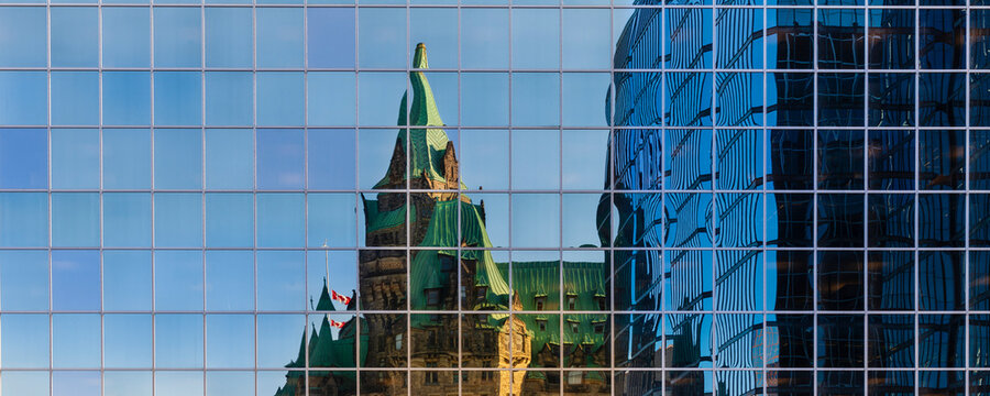 Canadian Parliament House reflected in the glass facade of a building in the nation's capital city of Ottawa; Ottawa, Ontario, Canada