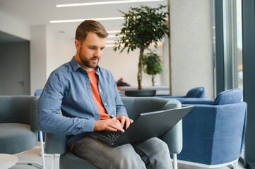 Handsome young businessman, using a laptop in the cafe.