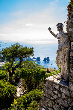 Statue of the Roman Emperor Tiberius with a view of Faraglioni Bay and rock formations from Monte Solaro on the Island of Capri; Naples, Capri, Italy