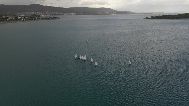 Training sailing yachts class optimist float on the sea.Yachting and sailing training. Summer sport. Aerial view top side of the blue sea and small training sailing yachts with athletes in the regatta
