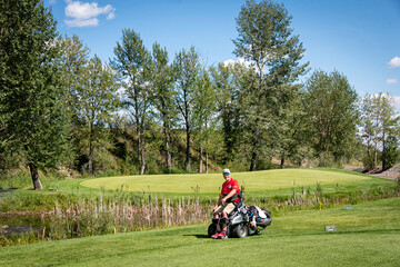 Disabled golfer using a specialized golf assistance motorized hydraulic wheelchair; Okotoks, Alberta, Canada