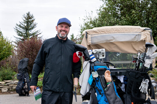 Golfer with arm prothesis standing beside a golf cart at a golf course; Okotoks, Alberta, Canada