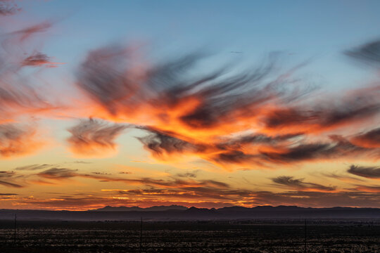 A sunset near Las Cruces, New Mexico with glowing cirrus clouds showing Virga effect; Las Cruces, New Mexico, United States of America