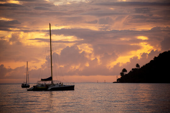 Sailboats anchored off shore at sunset; Tahaa, French Polynesia