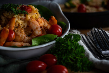 Shrimp scampi with pasta (orzo) garnished with parsley and grape tomatoes
