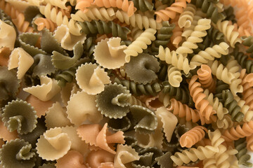 Flat lay of short pasta of various colors and shapes such as fusilli and daisies