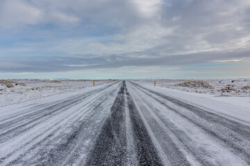 Strada rettilinea ricoperta di neve appena dopo una leggera nevicata con cielo nuvoloso
