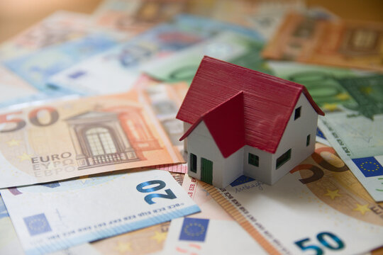 A miniature of a family house on euro banknotes represents the costs of buying or renting