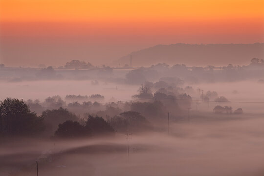 Misty dawn across the Somerset Levels, seen from the summit of Burrow Mump, a manmade hillock at Burrowbridge, near Langport, Somerset, Great Britain; Burrowbridge, Somerset, England