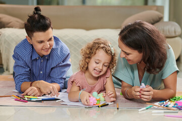 Obraz premium Happy mothers and little daughter playing with toys and drawing pictures together at home