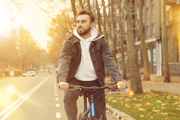 Happy handsome man riding bicycle in city on sunny day