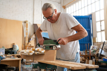 Carpenter working on wood craft at workspace producing wooden furniture with professional tools for crafting. High quality photo