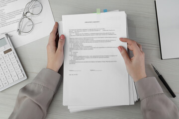 Woman reading documents, pen and glasses on white wooden table in office, top view