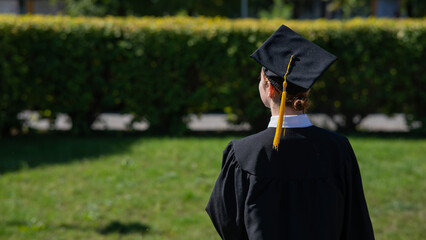 A woman throws her graduation cap against the blue sky.