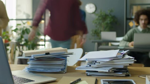 Timelapse of office workers stacking files and papers on desk of colleague who is absent