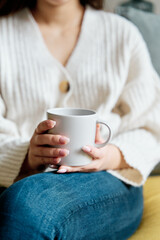 High angle of mug of hot beverage sitting on sofa and resting at home