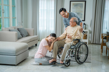 Senior man relaxing sitting on wheelchair in the living room at home,Cheerful family talking to old...